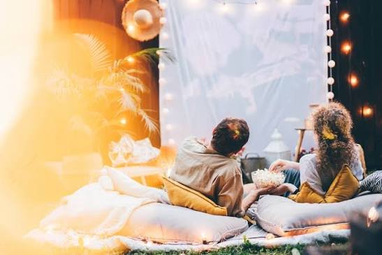Manta y artículos preparados para disfrutar cómodamente de una noche de cine al aire libre.